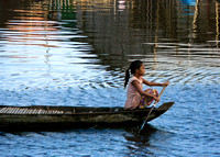 Girl rowing on boat in floating village
