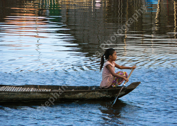 Girl rowing on boat in floating village